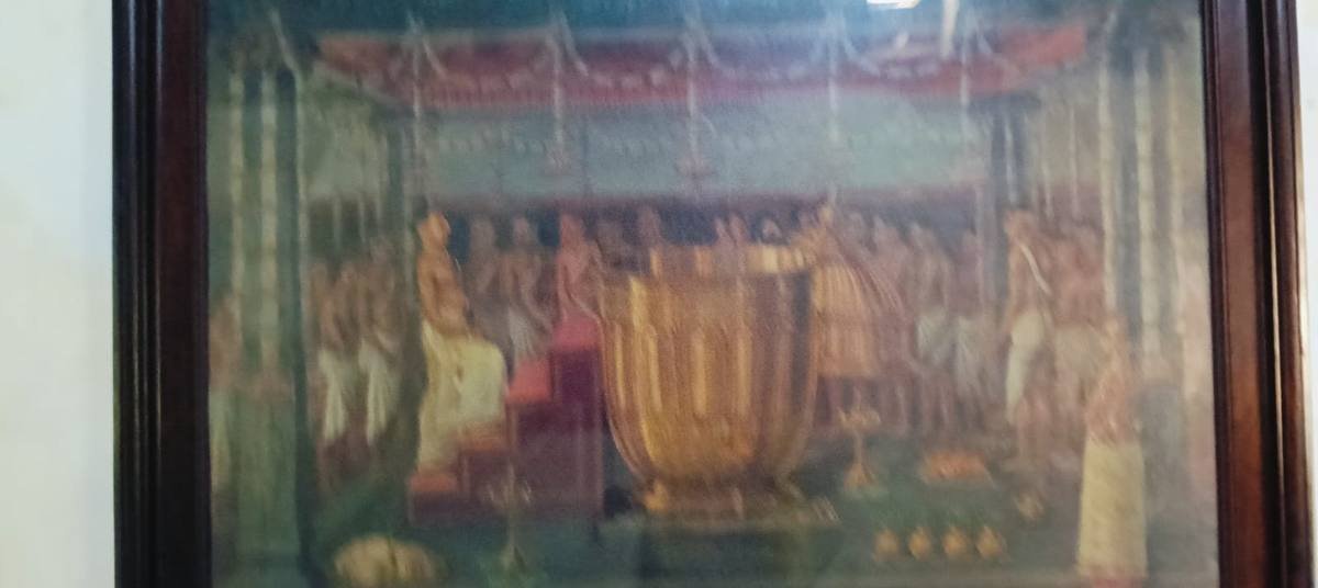 A framed painting of a temple ceremony hanging on a palace wall.