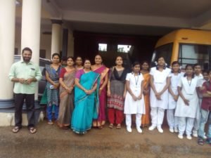 Staff and students standing beside the school bus.