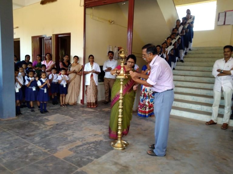 Staff lighting the brass lamp at a school gathering, pupils looking on.