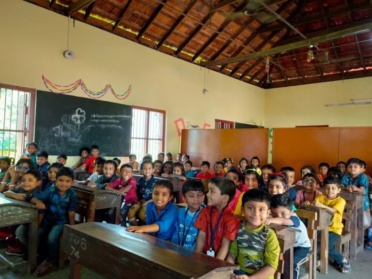 A pre-primary class seated at their benches in a decorated classroom.