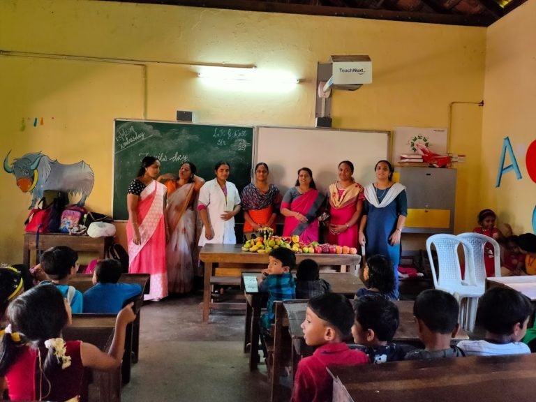 Staff standing together at a class event, a fruit display on the table before them.