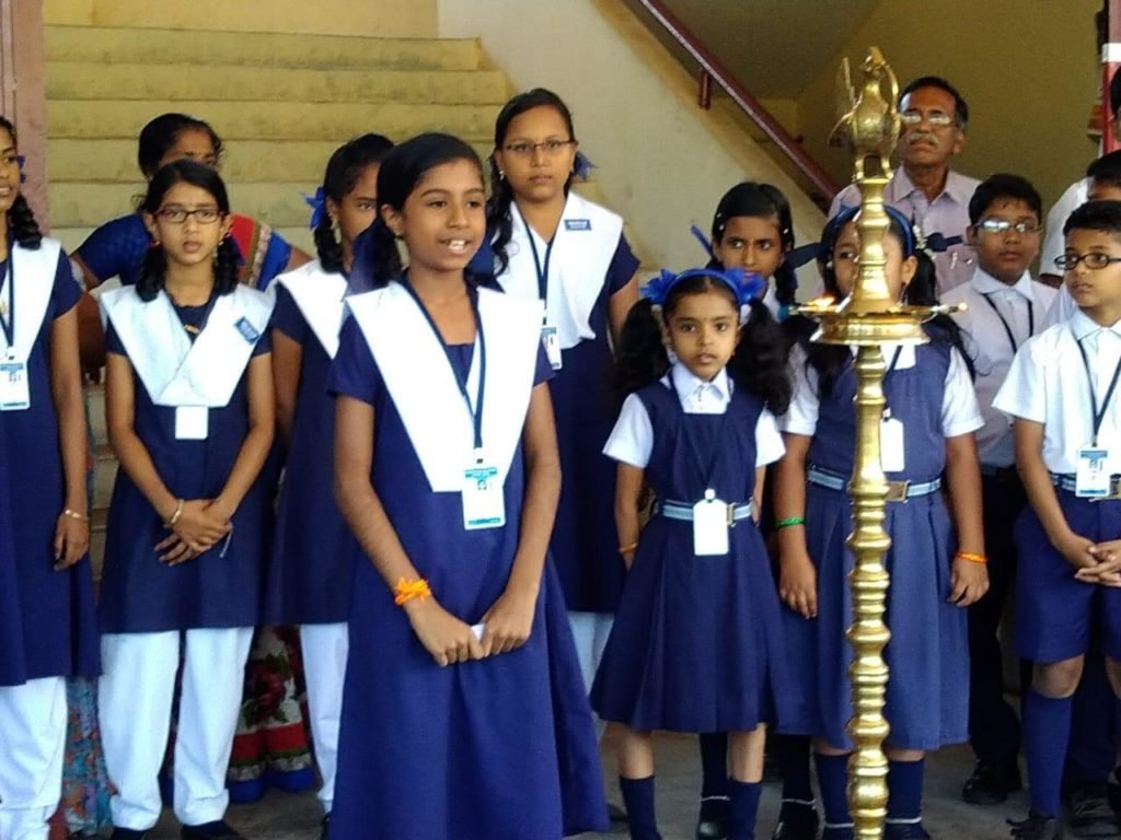 Students of T.D.B. Central School standing at assembly beside the lit brass lamp.